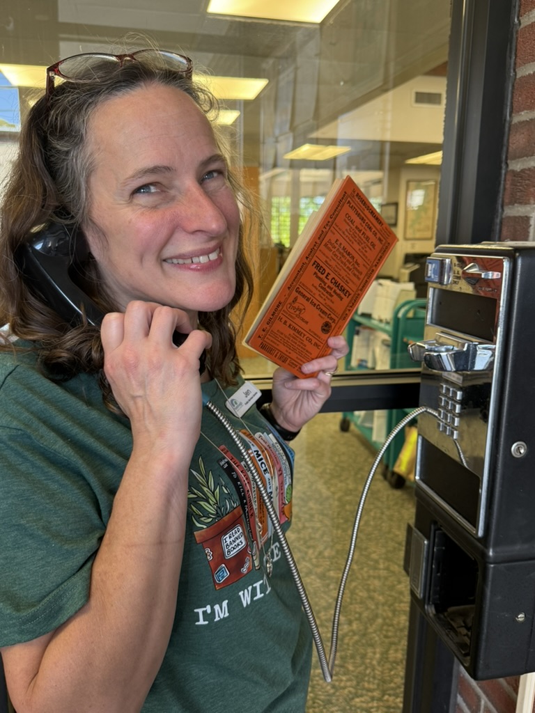 Brown haired woman on phone with orange covered city directory in her hand