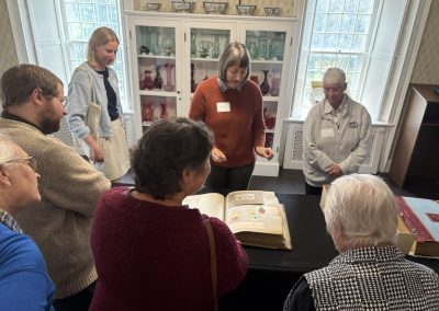 People gathered around a table with a scrapbook opened on it